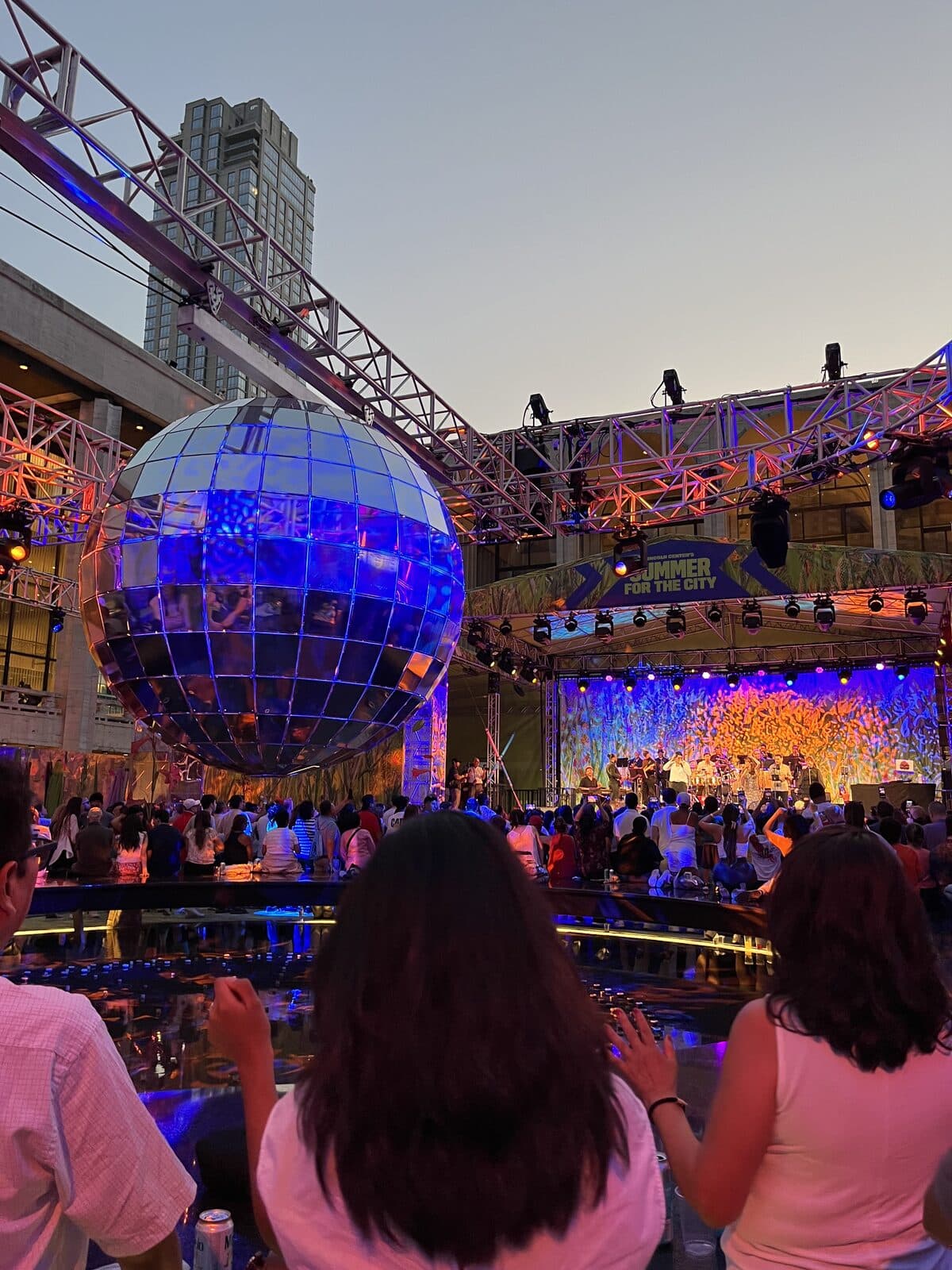 Crowd gathered at dusk beneath the disco ball during a live performance